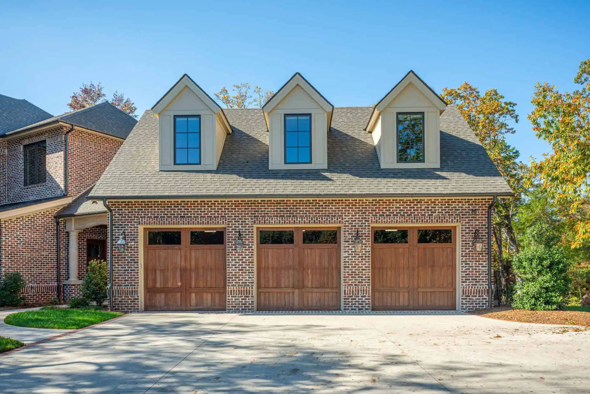 exterior shot of 3 car garage on classic red brick home with 3 windows above