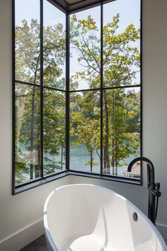 Stand alone tub overlooking trees and lake out of big window