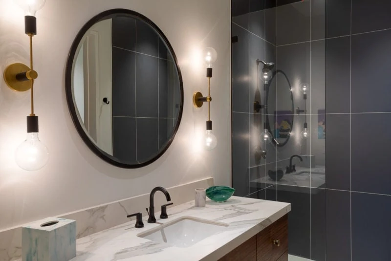 Vanity with circular mirror and grey slate tiled shower