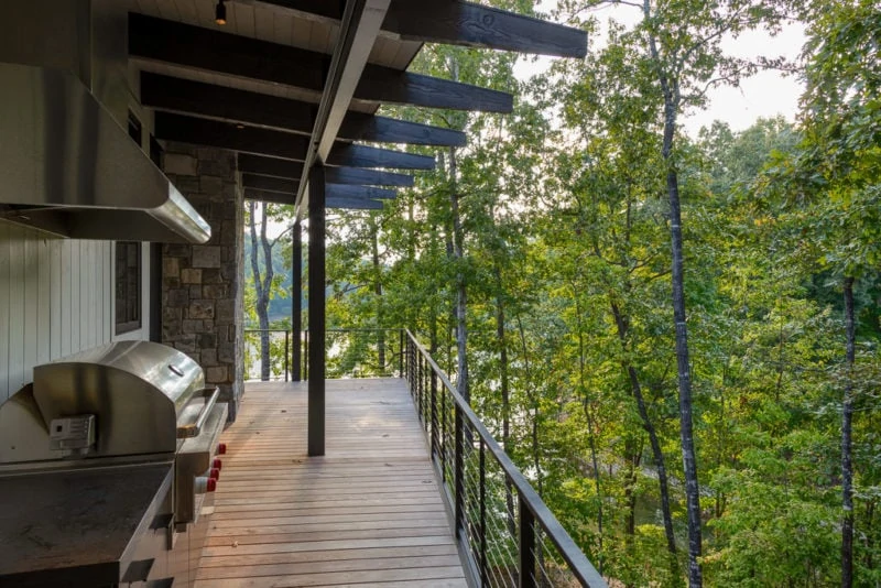 Outdoor patio with grill and view of trees and lake