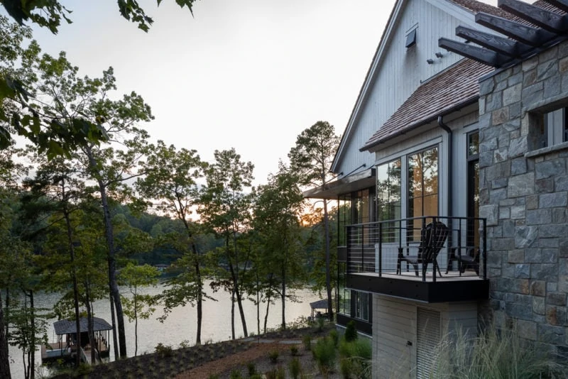 Balcony with seating, a dock, and sunset view of the lake