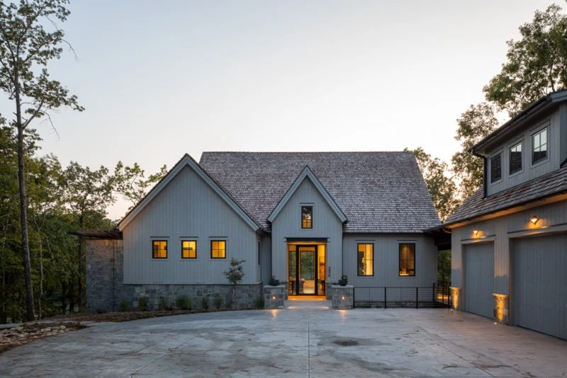 Grey custom home with coach lights and house lights on