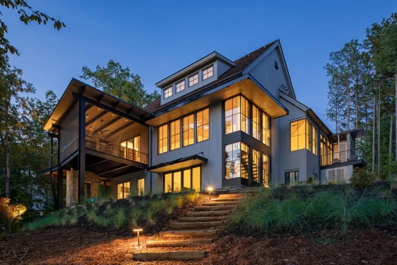 Backyard of custom home with cement steps and lights on in house