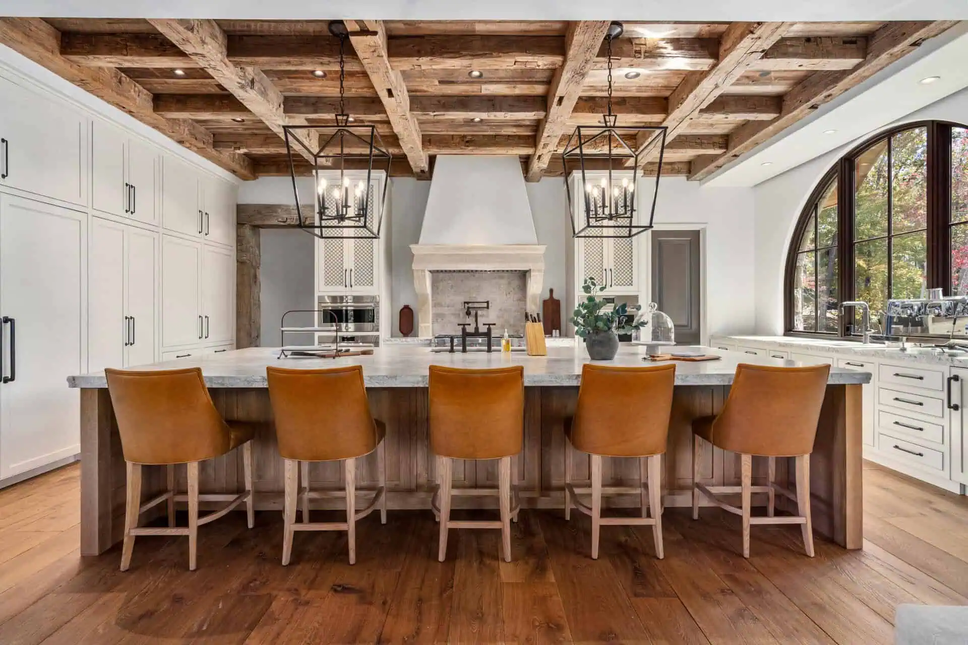 Ridgeline Design Studio interior design of large kitchen with massive island with bar seating, centered stove with range and detailed wood work ceiling
