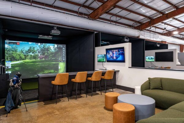 indoor golf simulator bay with lounge area behind