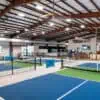 Indoor facility featuring pickle ball courts and golf simulator bay