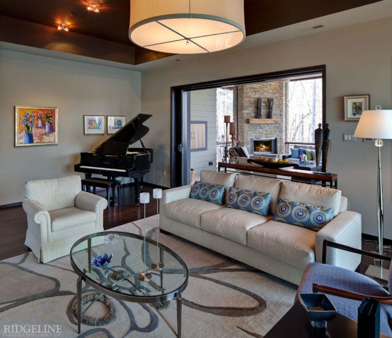 view of living room with glass coffee table, white couch, grand piano and open doors to outdoor balcony