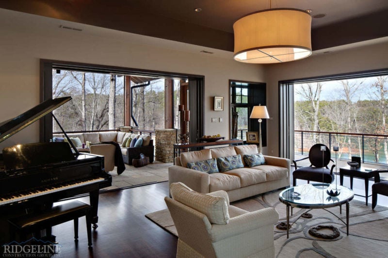 wide view of living room including open door to patio, piano and sofa