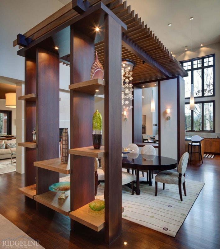 side view of dining room with floor to ceiling shelving unit acting as a wall