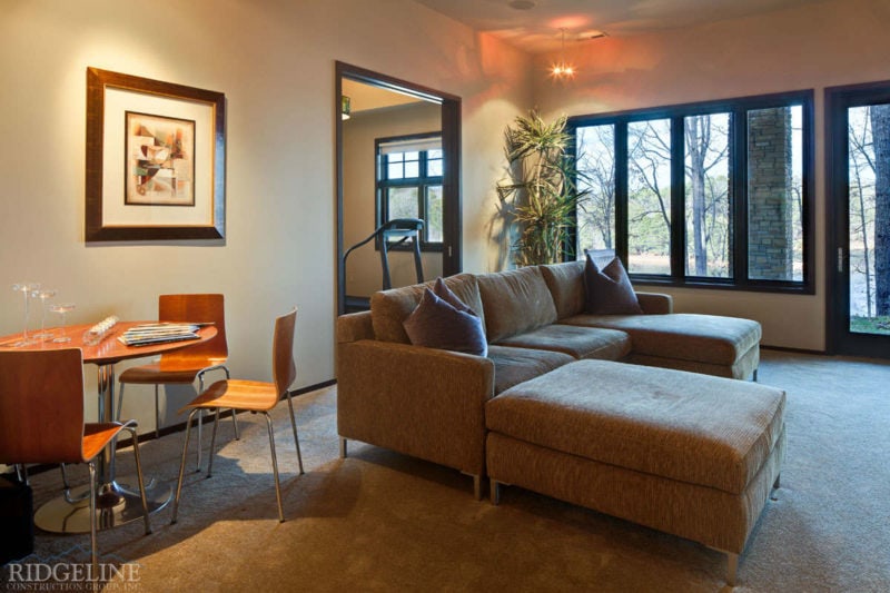 living room with sittin area small round table and chairs and big windows to wooded outdoors