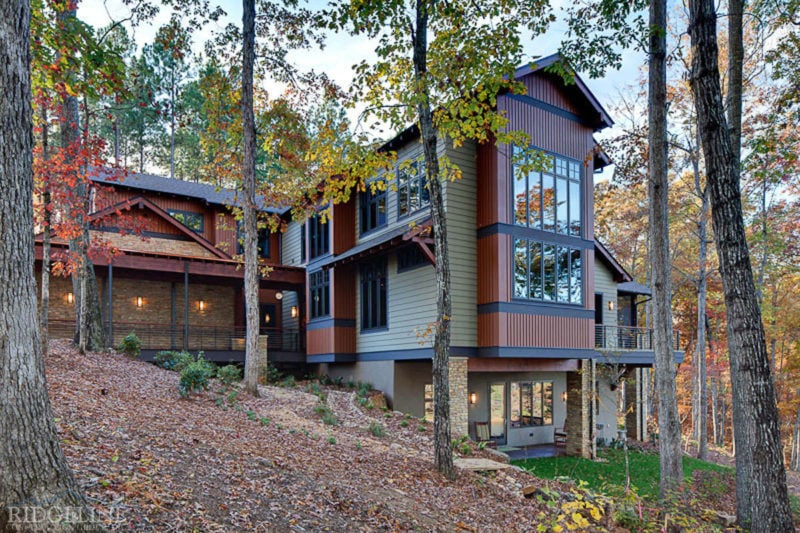 larger view of the back of a multistory house built on a hill in the woods