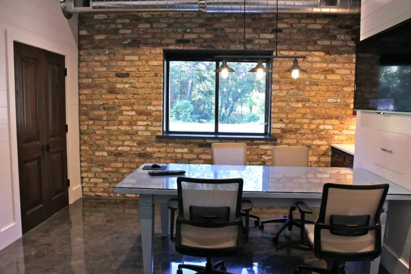 Office space with table, chairs, and brick wall