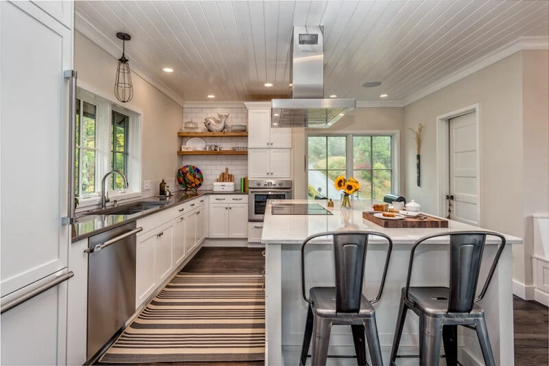 Kitchen Island with Chairs Around it With View of Appliances in Kitchen