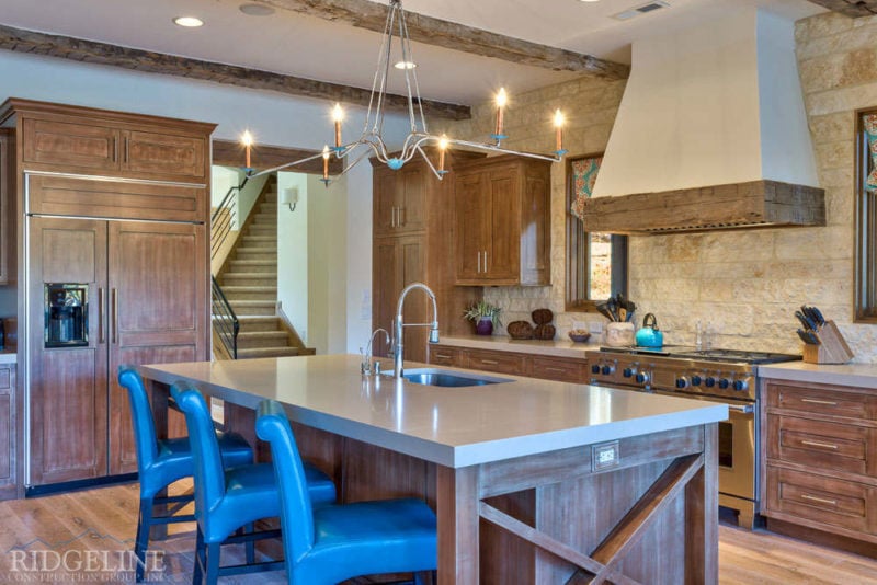 Island with sink and barstools in front of wood stained cabinets