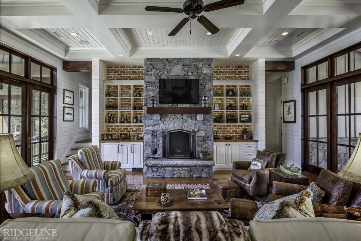 living room with green and brown furniture, stone fireplace and white built in cabinets surrounding