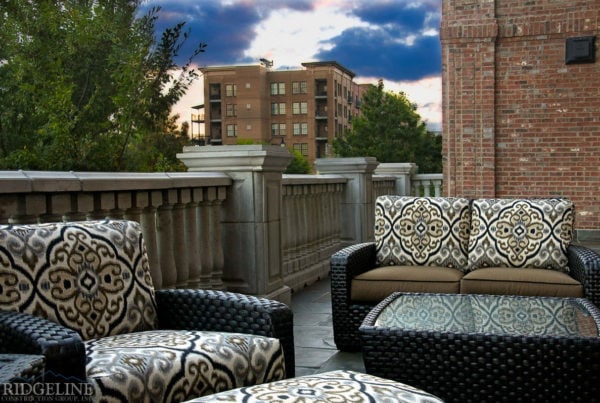 wicker patio furniture with printed cushions on patio with stone railing