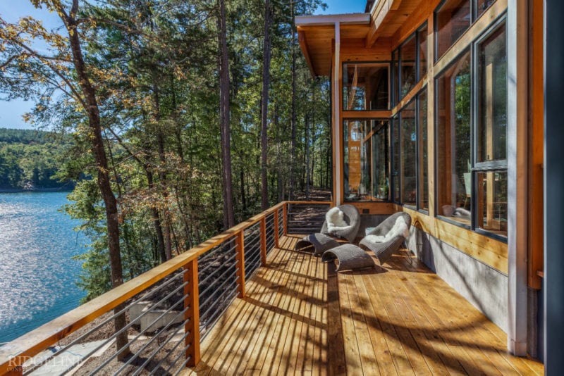 patio of modern mountain home with lounge chairs overlooking lake