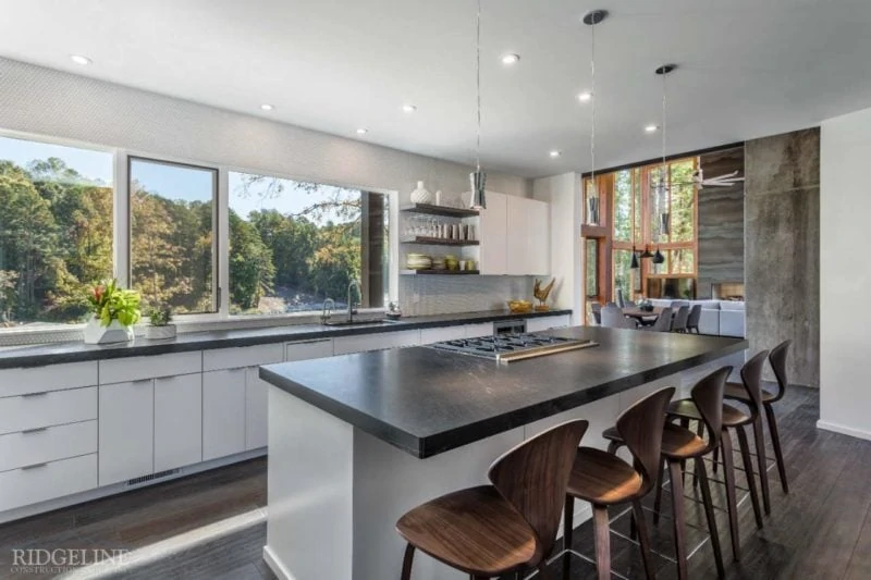 Custom kitchen with an island and black countertops, overlooking a forest