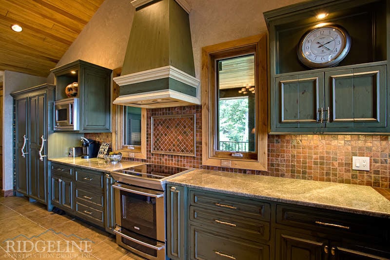 Mountain house kitchen with green cabinets and stainless stove