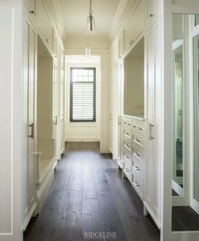 hallway with white walls, white cabinets, and brown wood floors