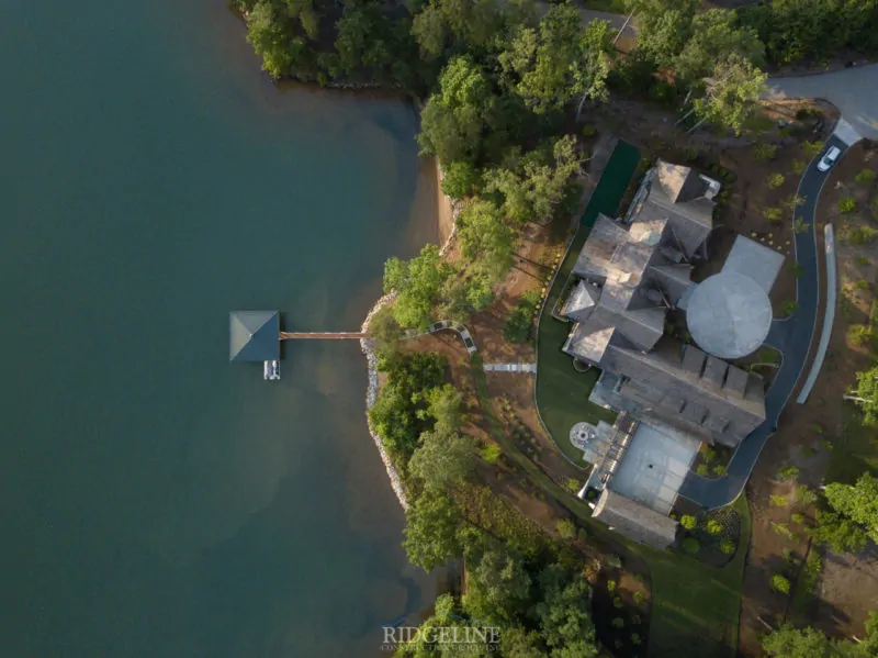 aerial view of mansion with putting green and fire pit on lake keowee