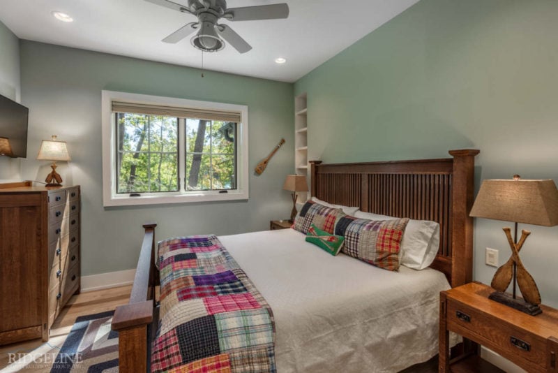 bedroom with colorful quilt on bed and brown furniture