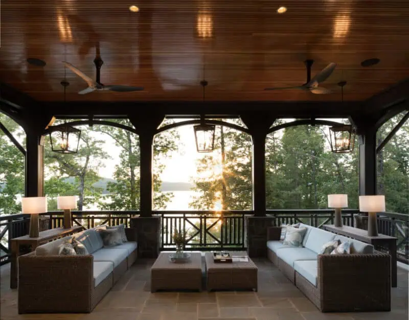covered outdoor porch with large seating area and coffee table overlooking water