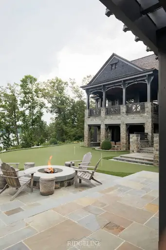 outdoor fireplace with chairs around on mini golf course in backyard of mansion