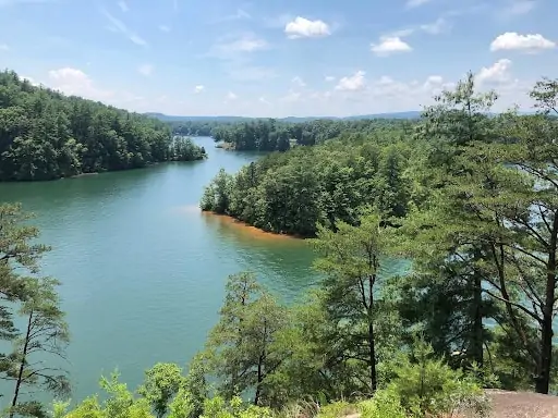 teal colored lake with evergreen trees in south carolina mountains