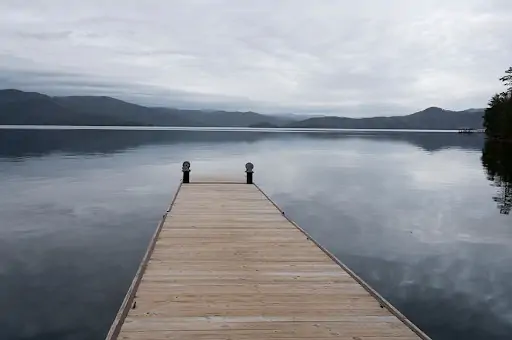 long wooden dock going out into lake with south carolina mountains around